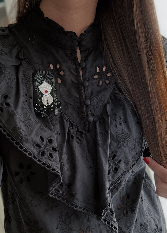 Black embroidered blouse with a beaded Wednesday Addams portrait siluette brooch.