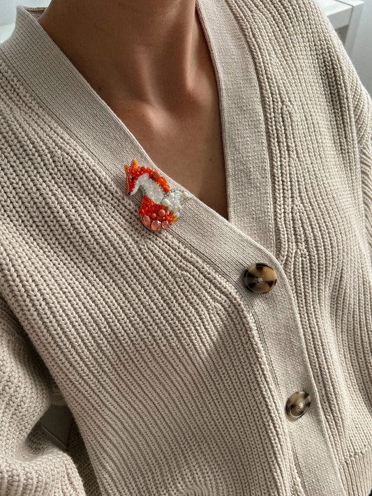 Close-up of beaded fox brooch on a beige cardigan.
