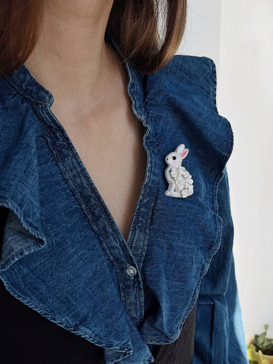 Blue denim shirt with a white bunny rabbit brooch.