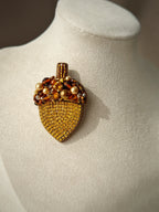 acorn brooch with gemstones on a mannequin bust