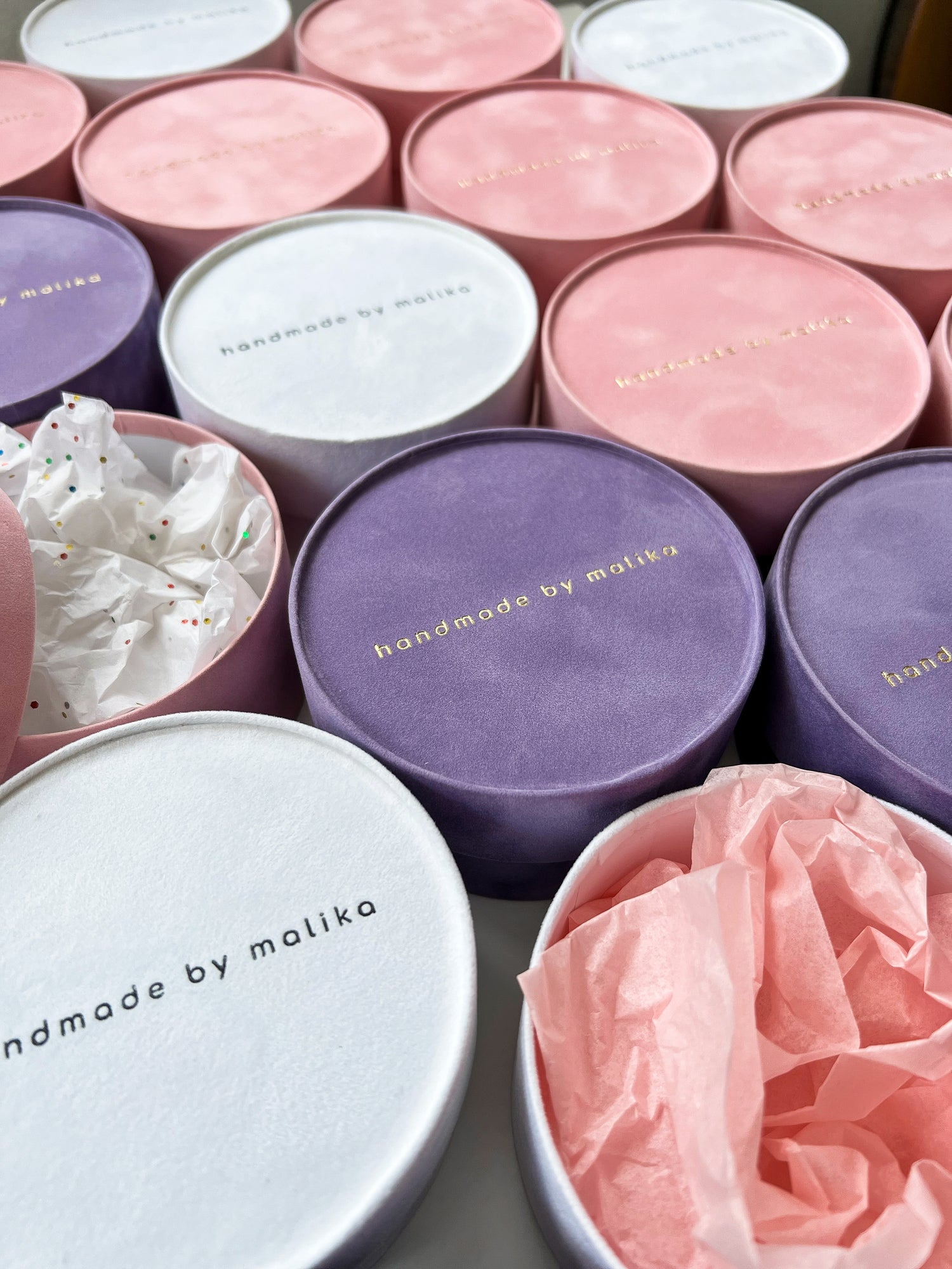 Collection of round jewelry boxes with 'handmade by malika' branding on it.