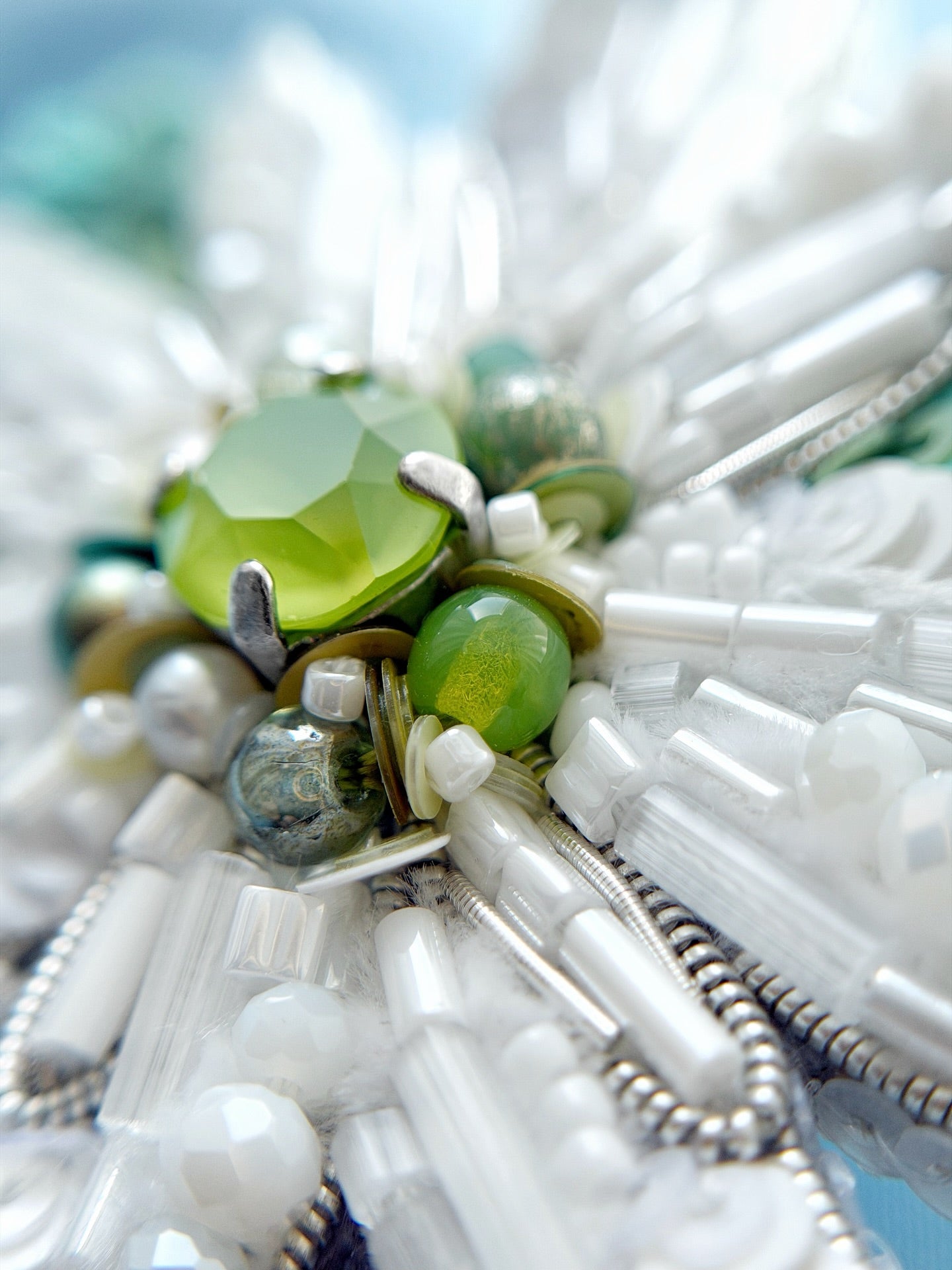 Close-up of a beaded edelweiss flower with green and white beads against a blurred natural background