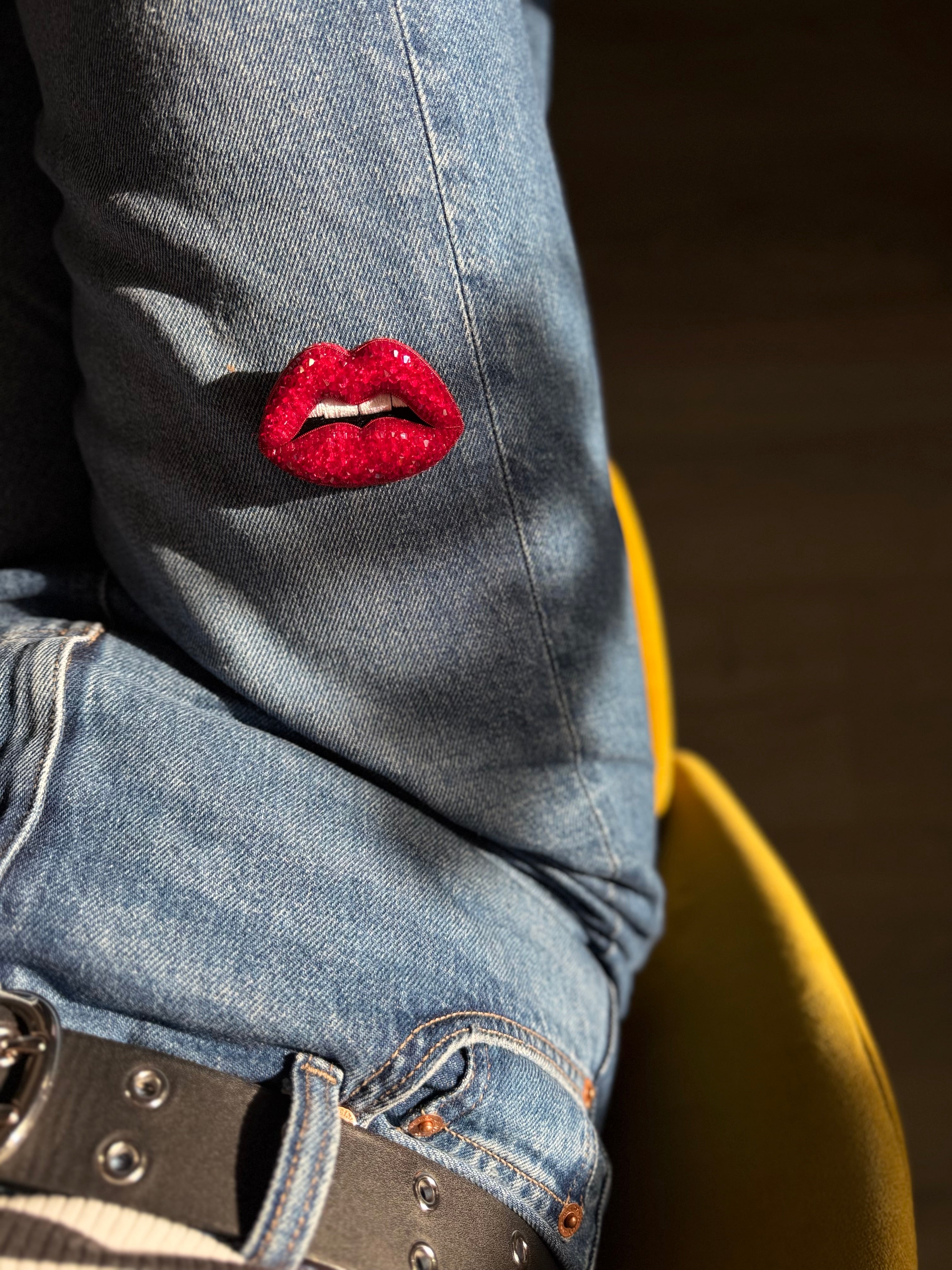 Red lip brooch displayed on a denim 