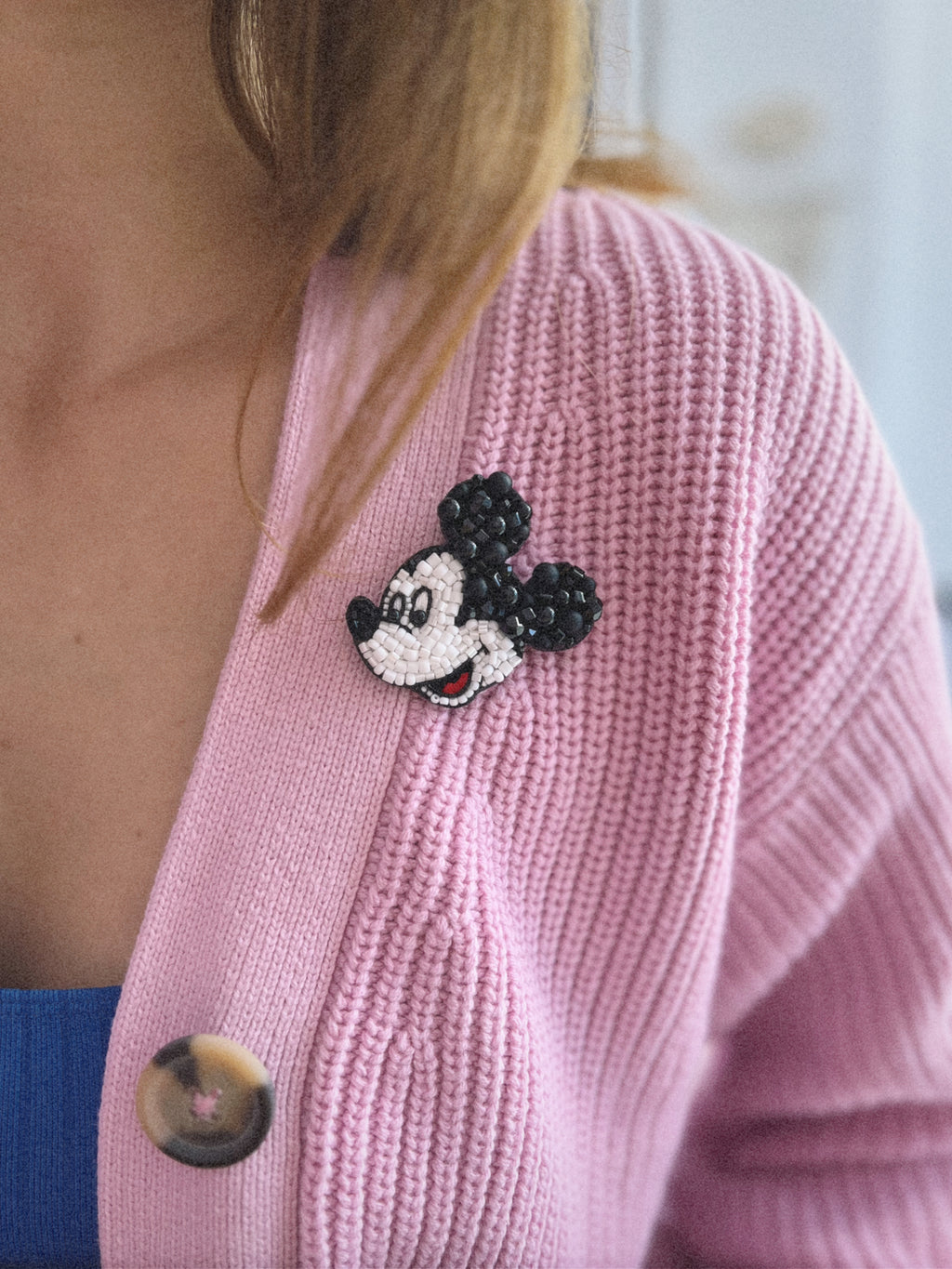 Pink knitted cardigan with Mickey Mouse beaded brooch on it