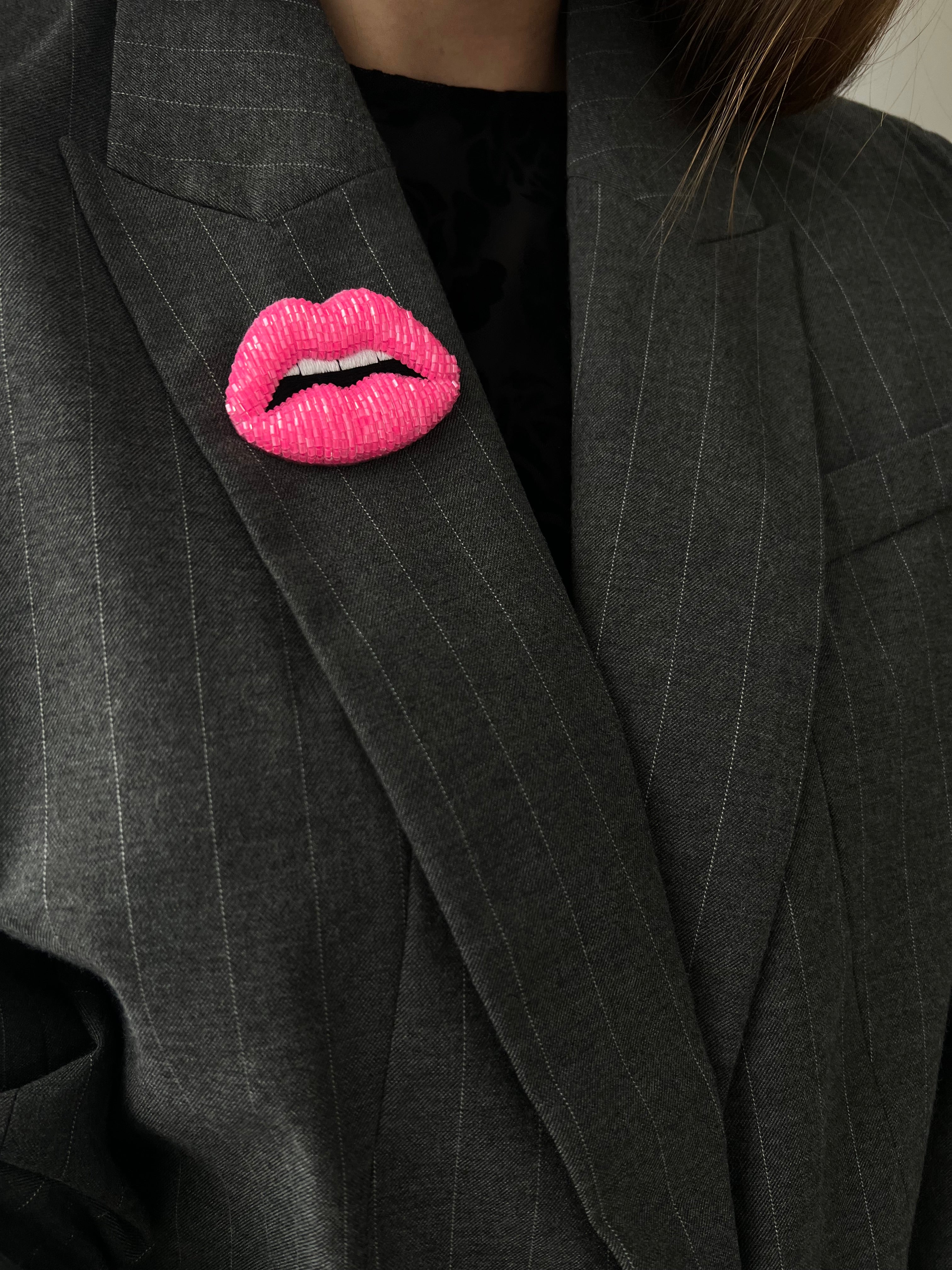 Gray suit jacket with a pink lip shaped brooch