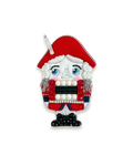 Nutcracker brooch with red hat and traditional attire.