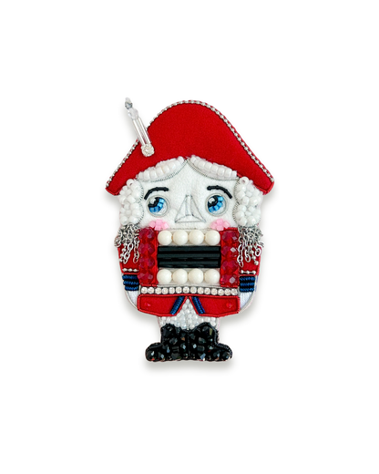Nutcracker brooch with red hat and traditional attire.