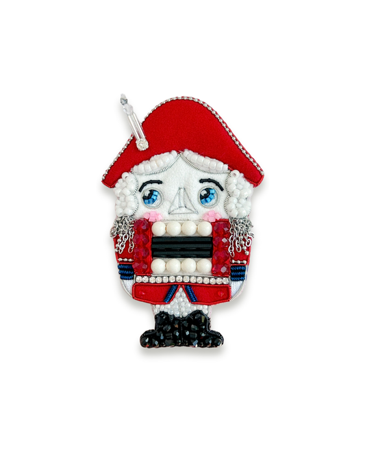 Nutcracker brooch with red hat and traditional attire.
