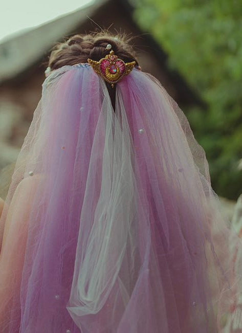 Bride wearing a pink veil with a Sailor Moon Crisis moon brooch outdoors